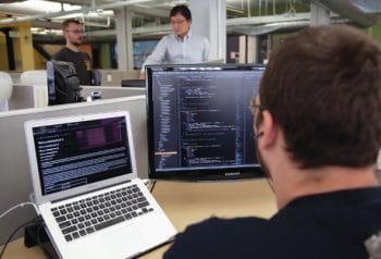 programmer working on laptop and desktop
