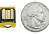 The Bitmerse Romu next to a coin, highlighting its ultra-compact $15.5 \times 12\text{ mm}$ form factor designed to fit entirely inside a USB-A port