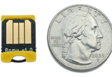 The Bitmerse Romu next to a coin, highlighting its ultra-compact $15.5 \times 12\text{ mm}$ form factor designed to fit entirely inside a USB-A port